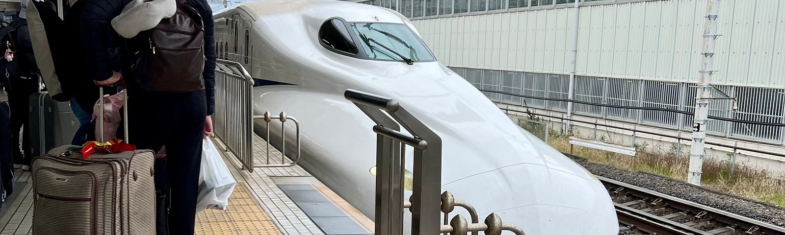 Shinkansen pulling into a station with minimal barriers.