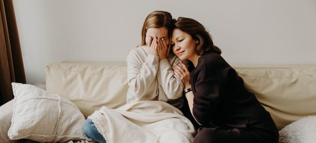 A delusional mother smiles as she embraces her suffering daughter.