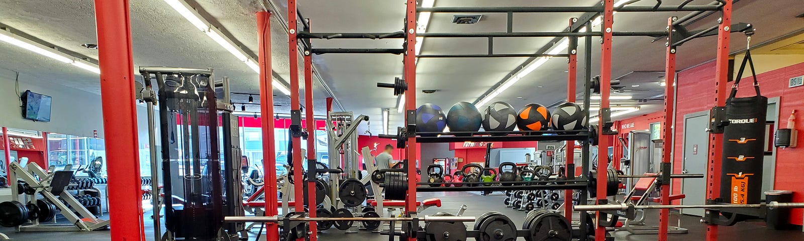 Brightly lit gym with weight equipment and machines.