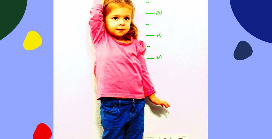A little girl in front of a measuring wall for growing up