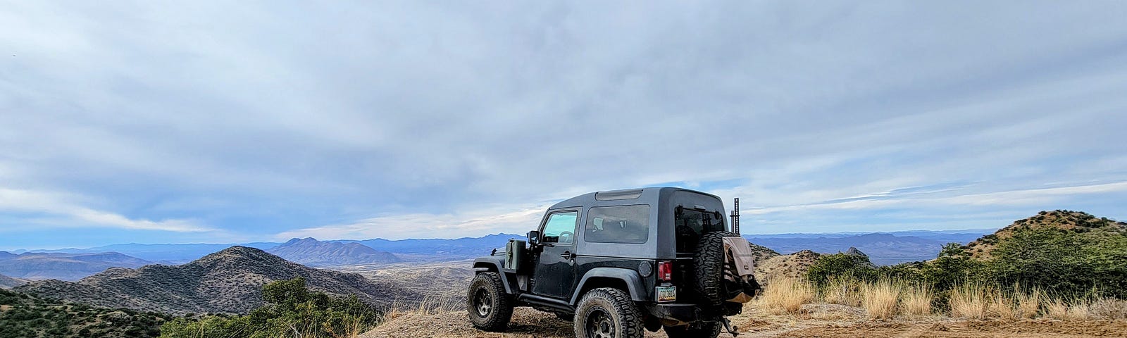 Black Jeep parked on a dirt road looking out over mountain ranges in southern Arizona