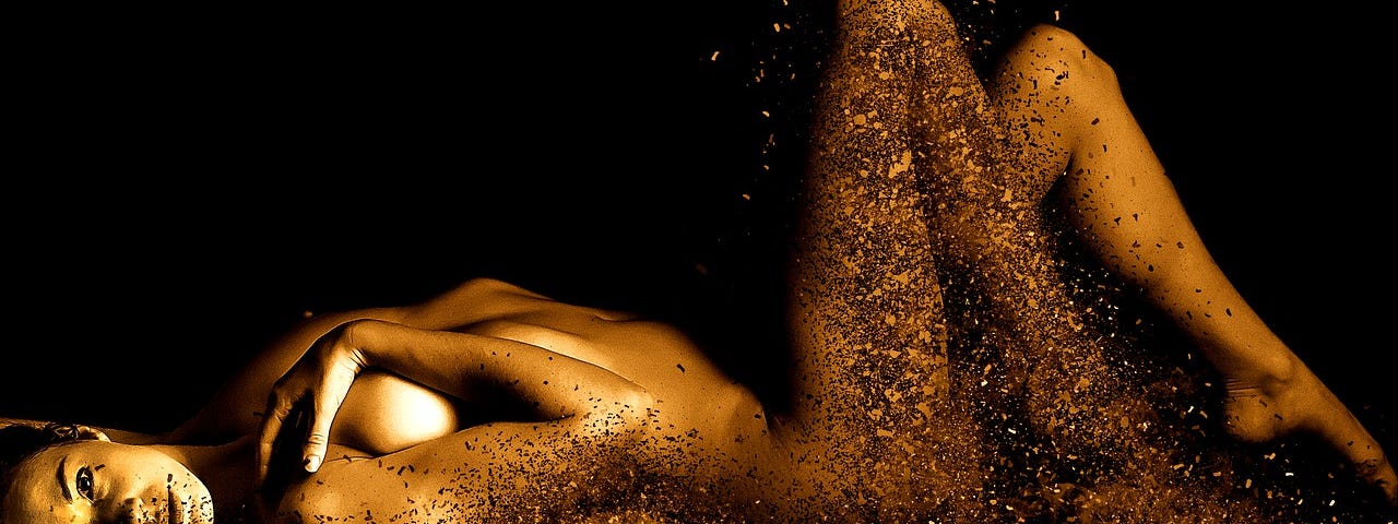 A naked woman adorned in golden light as she is shattered into shards by desire.