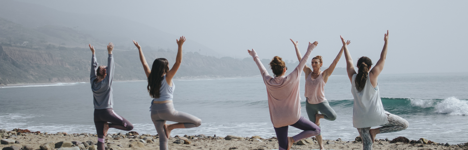 A group of women doing yoga on the beach