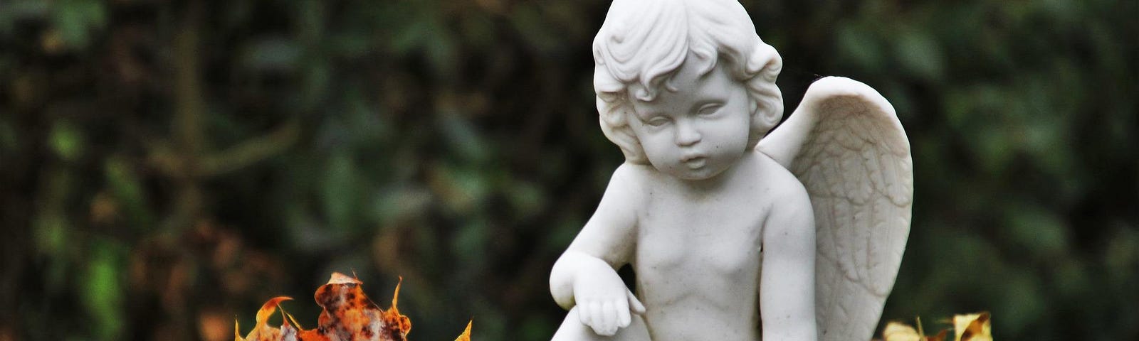 Stone cherub sitting on top of gravestone