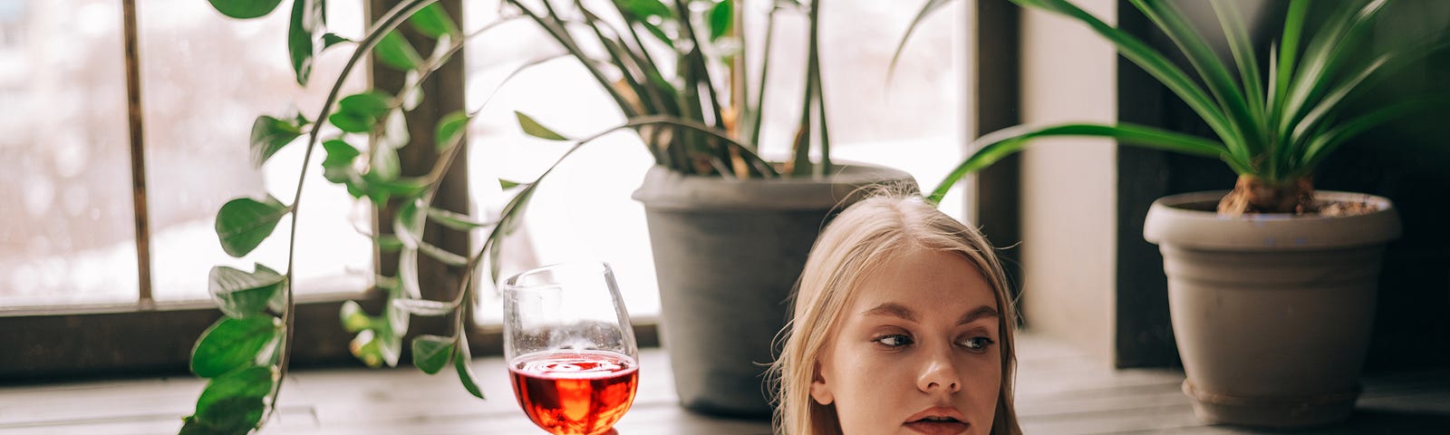 Woman drinking wine in a bubble bath. The bubbles cover her breasts, but she’s obviously looking at something or somene.