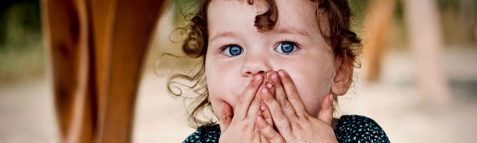 Little girl with hands over her mouth