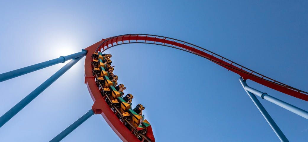 A rollercoaster flashes through a loop in the afternoon sun.