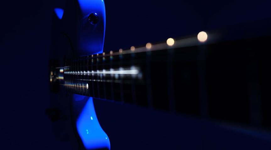 Close-up of blue bass guitar neck in low light
