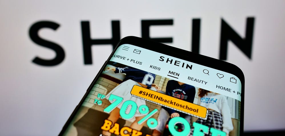 IMAGE: A cellphone with online shop of Chinese e-commerce company Shein on screen in front of business logo