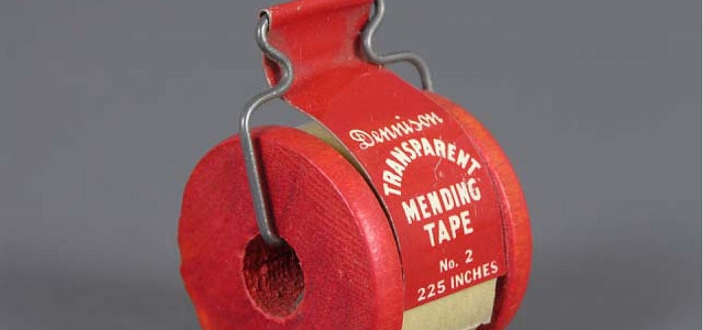 A red tape dispenser with the brand name Dennison on it and a text“Transparent Mending Tape” no 2