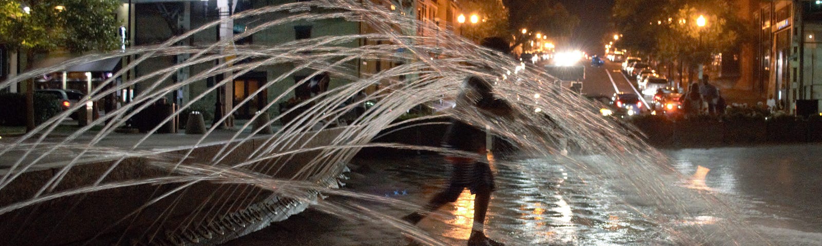 child running through water fountains