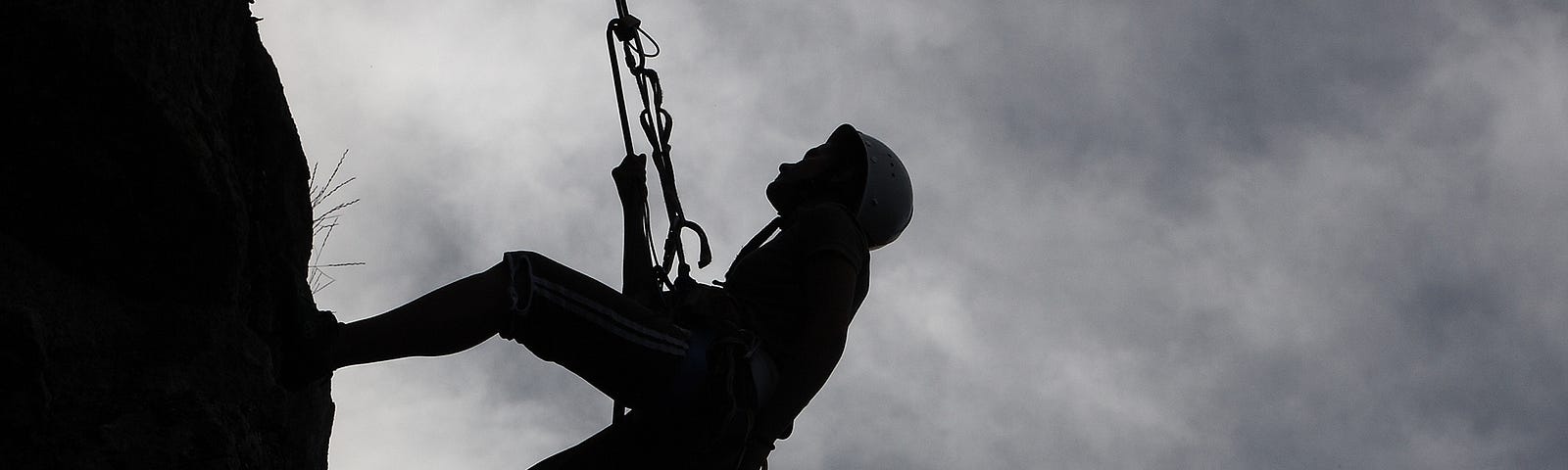 Teenager rappeling on side of moutain with eagle flying in distance