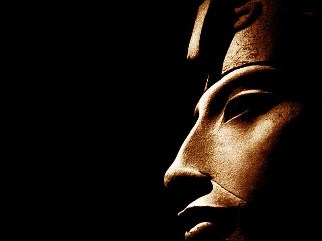 A profile of a statue of an Egyptian Pharoah, set against a black background