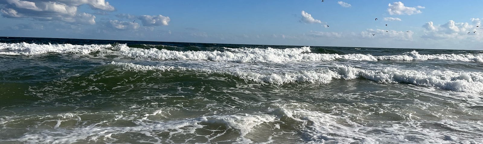 A picture of the ocean midday, as waves recede. Nothing but sky in the background.