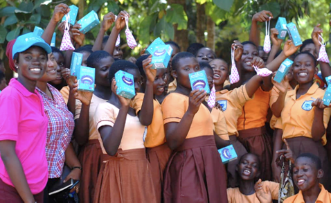 A group of girls in Ghana holding menstrual cups in the air