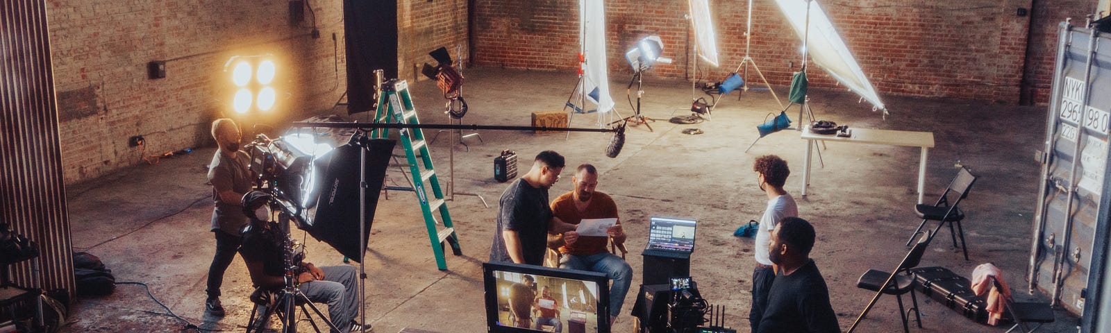 An overhead view of a film crew shooting in a warehouse with windows along one wall.