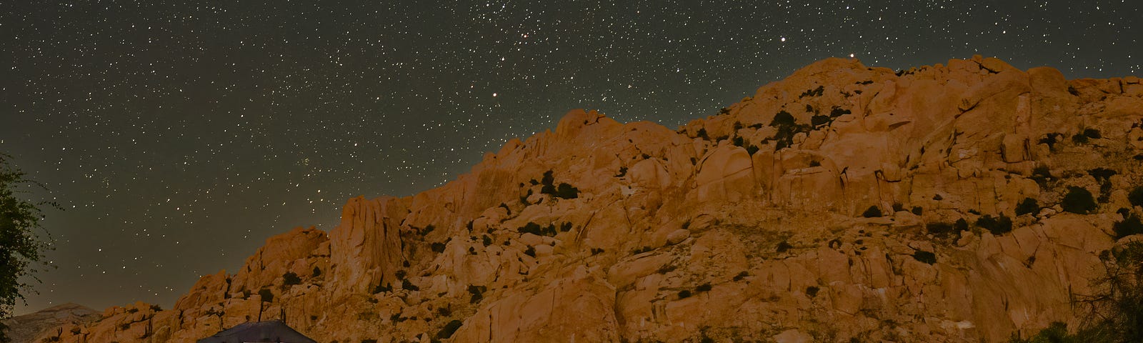 A teardrop trailer and tent in front of mountains and a starry sky