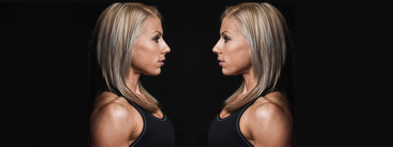 A woman looking at her mirror reflection for How Your Reflection Can Help You Eat Less, Lose Weight, & Tell the Truth