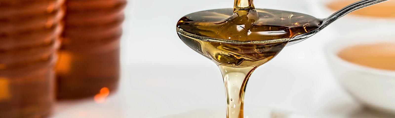 closeup photograph of maple syrup being poured into a bowl and spoon
