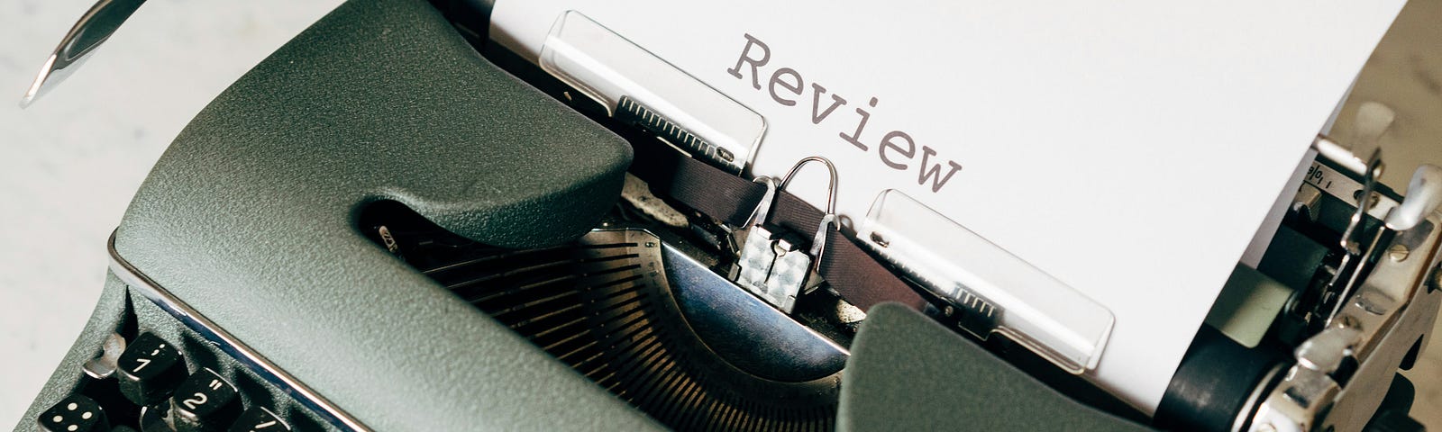 A typewriter has paper with the word, “Review,” written.