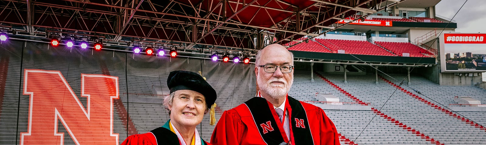 Vanessa and Bob take a photo on the stage inside the stadium ahead of undergraduate commencement