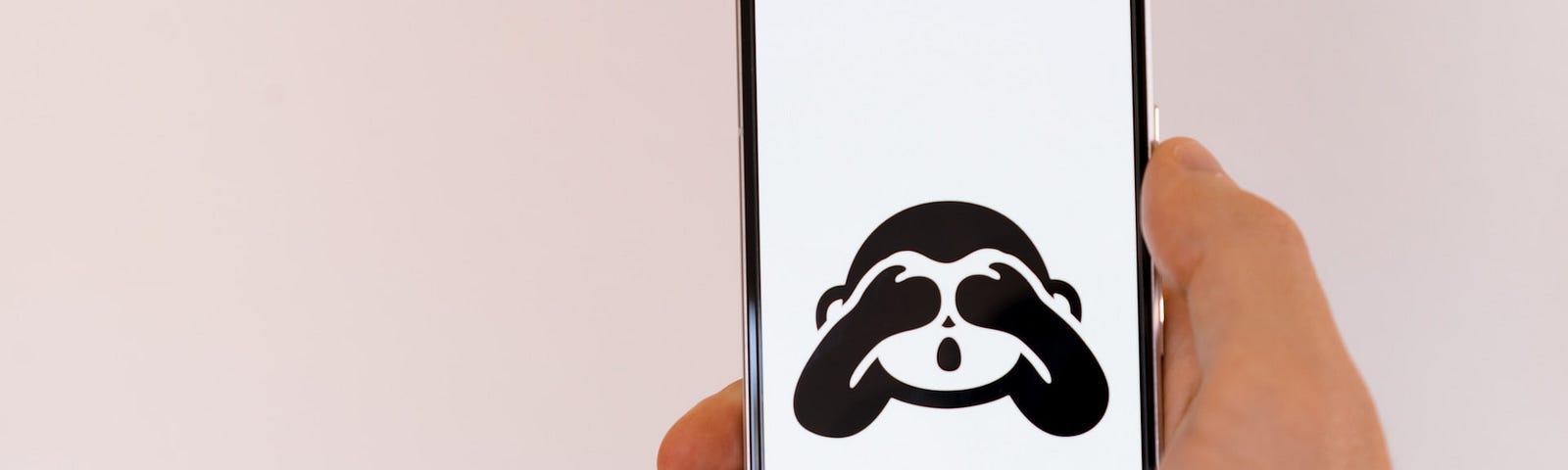 IMAGE: A hand holding a smartphone with an drawing of a monkey covering its eyes with its hands