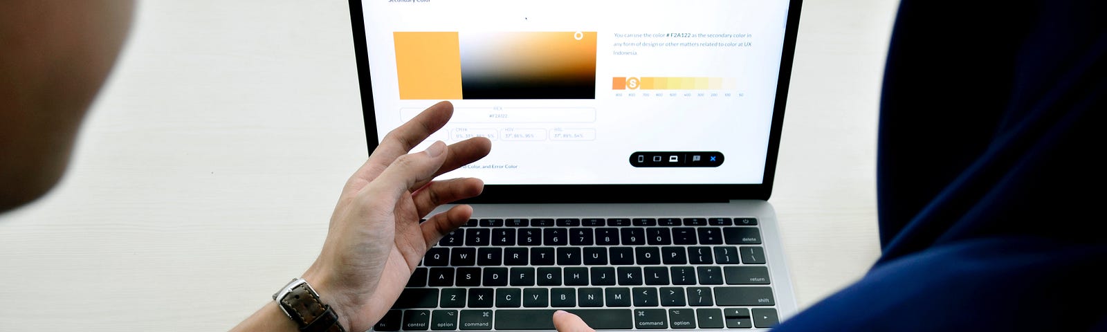 Two people are discussing an interface draft in front of a laptop