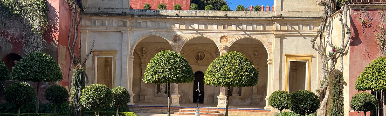 The well-manicured yard of a 16th century home including benches and a fountain