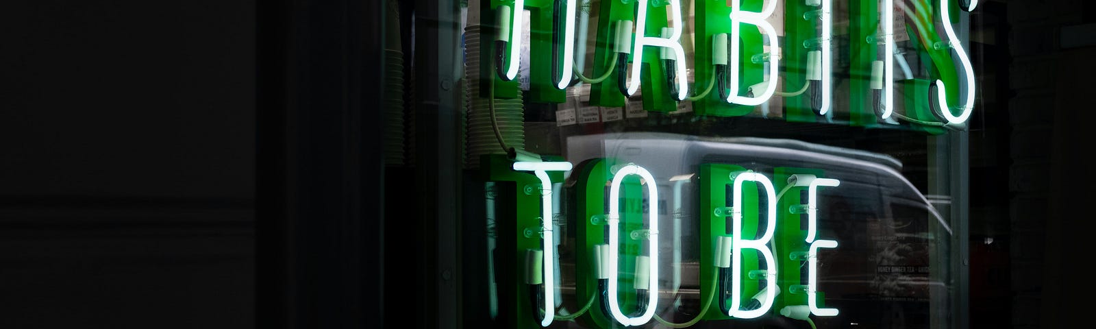An illuminated neon sign saying “Habits to be made”