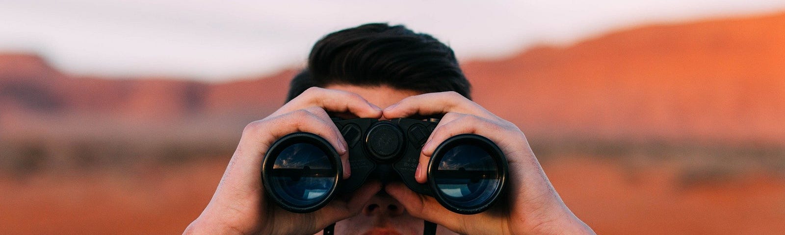 Man looking towards you through binoculars