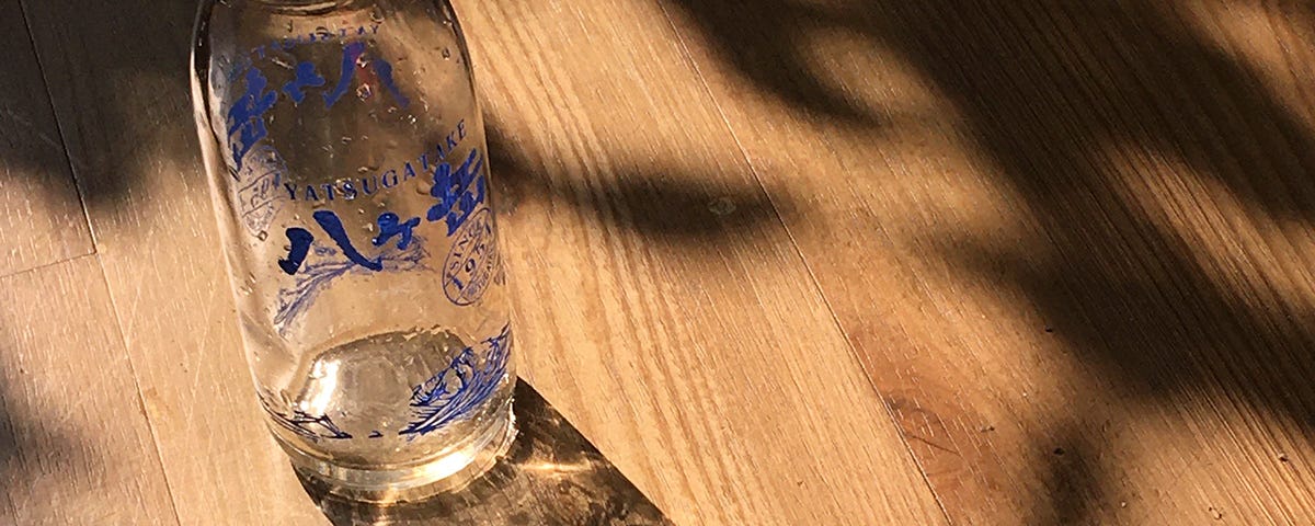 An empty milk bottle projects a crystal effect shadow when sunlight passes through.