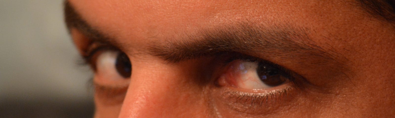 A man’s angry eyes stare closely into the camera.