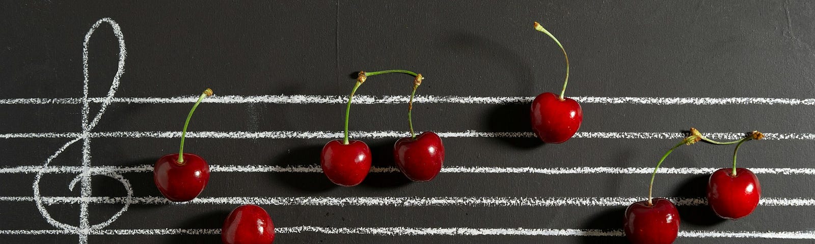 A musical staff written on what looks like a blackboard with cherries as music notes
