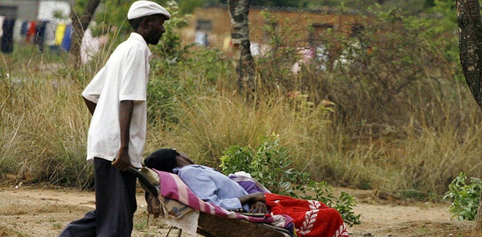 a man transporting his ill wife to a nearby clinic (5km away) in a wheelbarrow