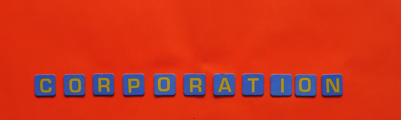 The word “corporation” spelled out in blue tiles on a red surface.