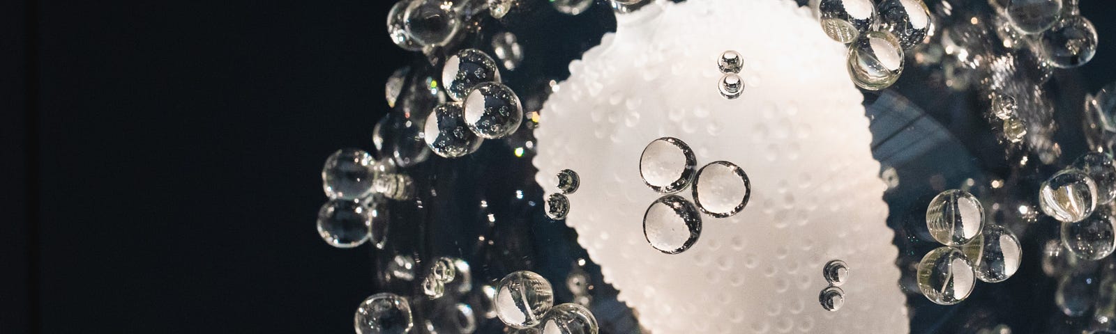 A close-up photograph of a sculpture of a microbe made of glass.