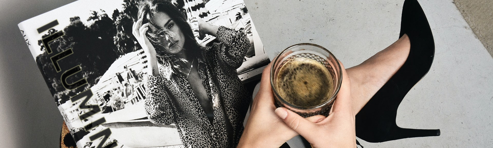 A woman having a cold drink while holding a magzine with title: Illumination