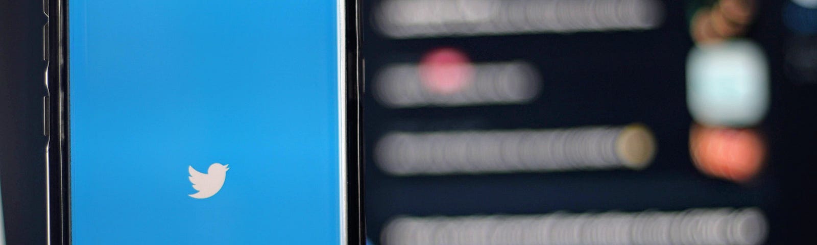 A mobile phone shows the Twitter app with a blurred screen behind it with various posts.