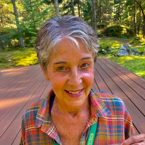 Author standing on her deck holding up a Bombers coaster and graduation photo on a lanyard