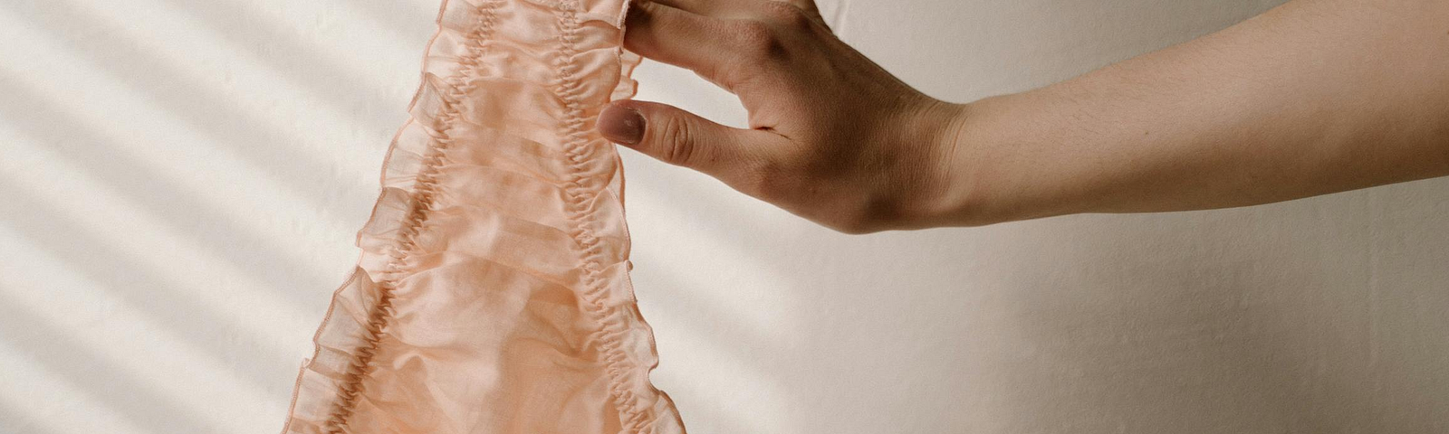 Woman’s hand holding peach lacey panties