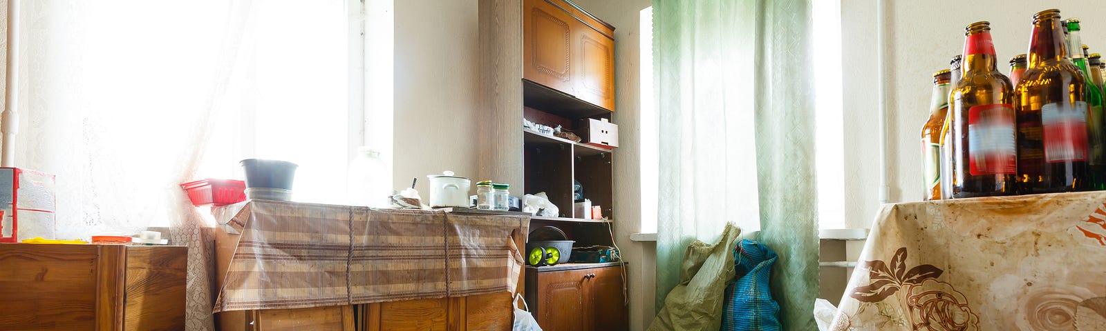 Room in house with old style furniture, cluttered surfaces and bagged up junk