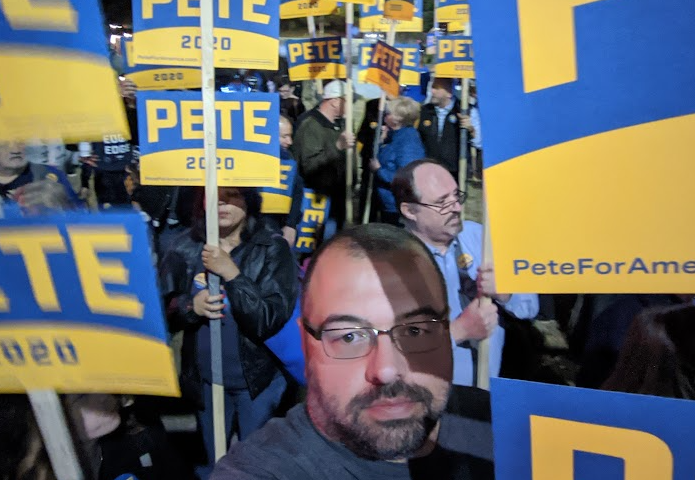 A group of people holding yellow and blue voting signs.