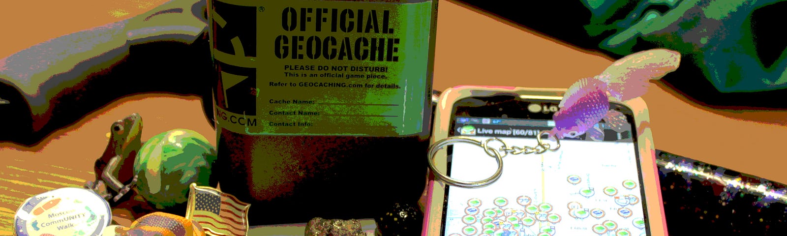 Photo of small geocache container surrounded by small knick knacks, next to a smartphone with a map displayed on the screen