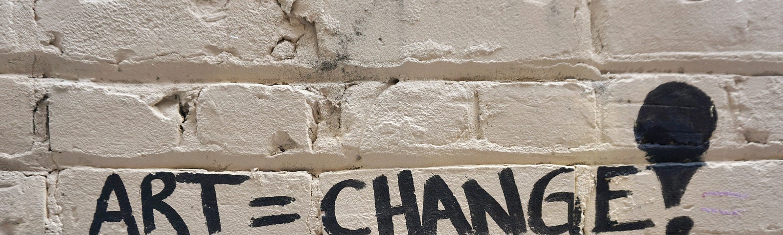 Writing on white wall, that says: Art equals change.