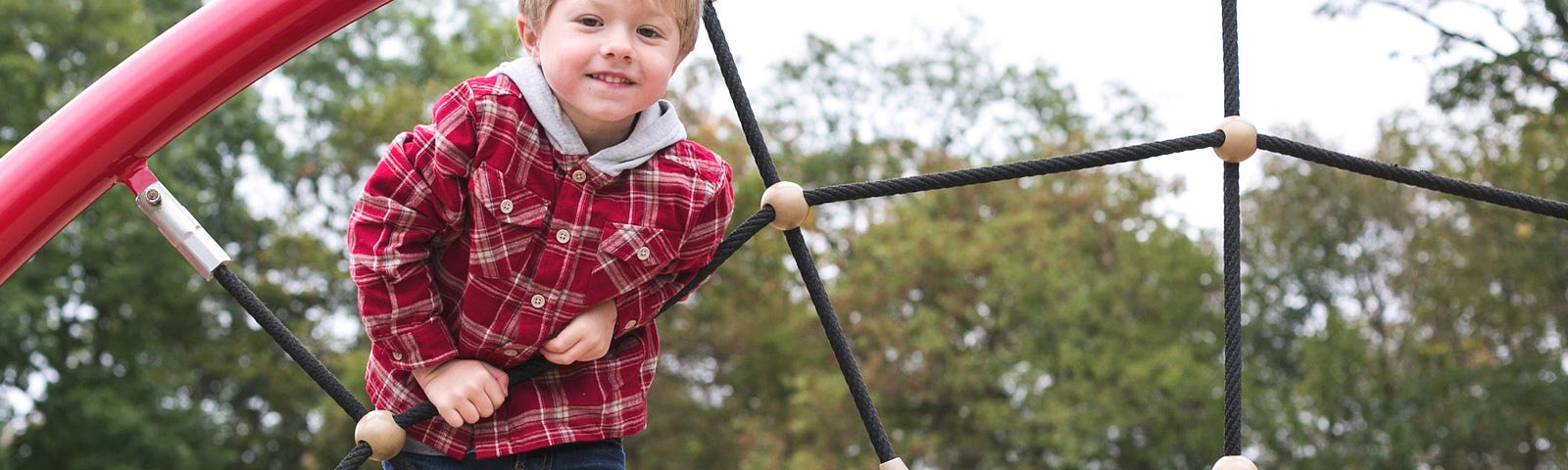 Young boy climbing on playground web