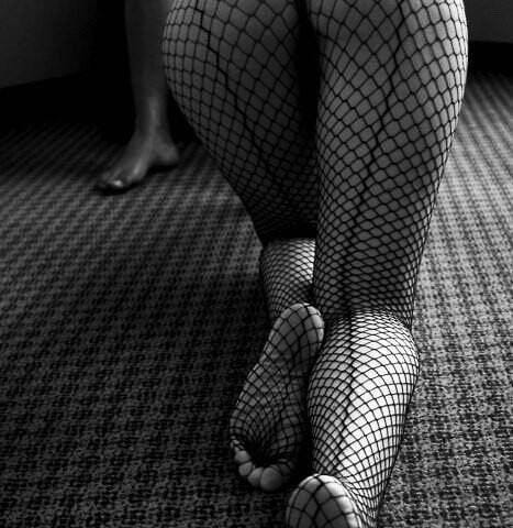 A woman’s legs in whale net stockings are seen from behind as she crawls toward a man waiting