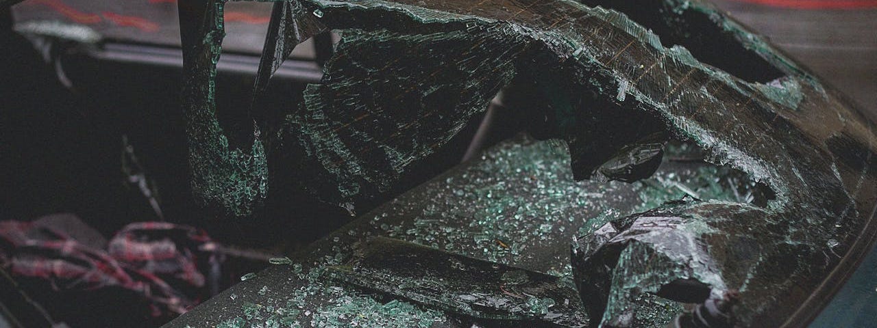 A blue vehicle with a smashed windshield.