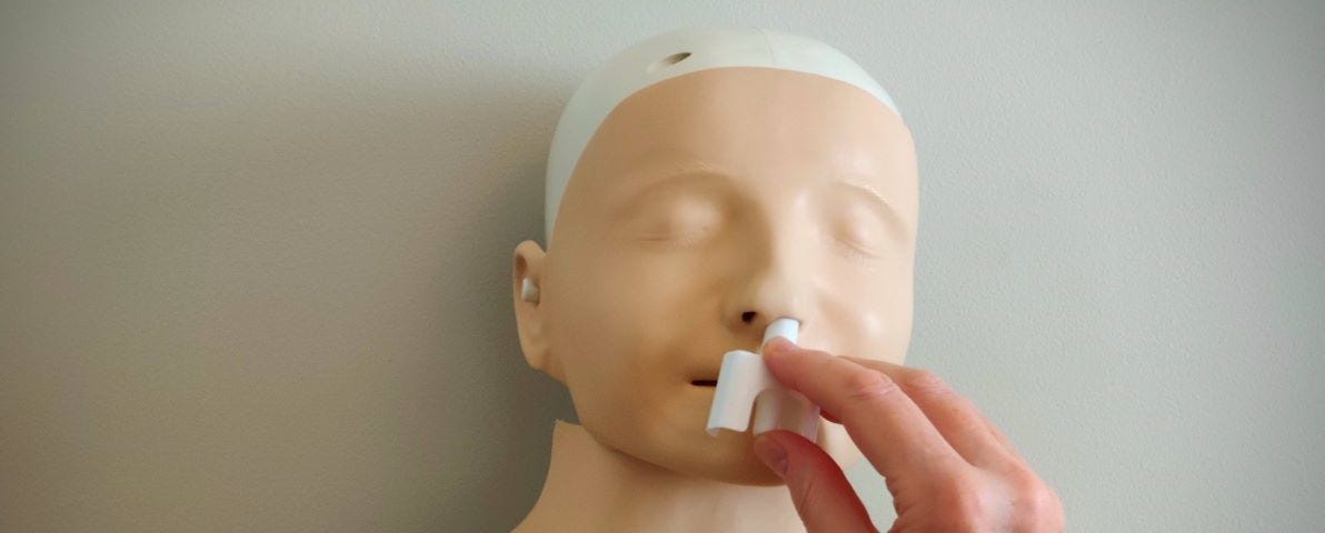 A person inserts a nasal spray into a CPR manikin’s nose to demonstrate the administration of adrenaline to a person suffering from anaphylaxis.
