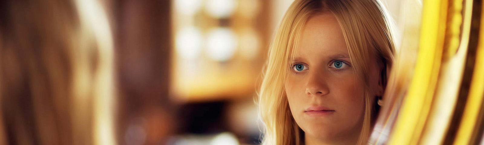 young woman looking at her face in the mirror.