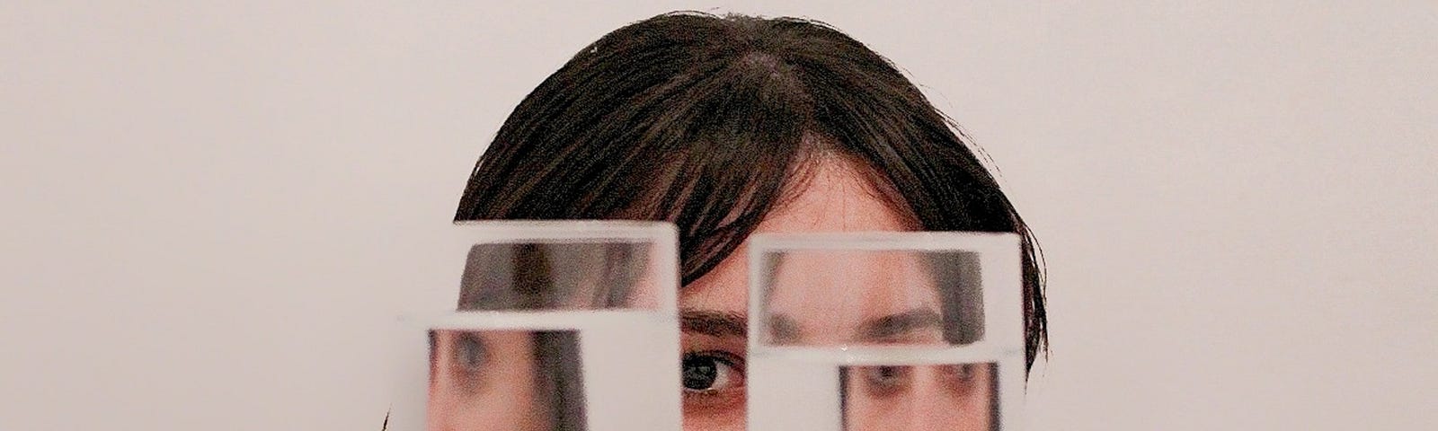 Girl hiding behind two full glasses of water that distort her perception